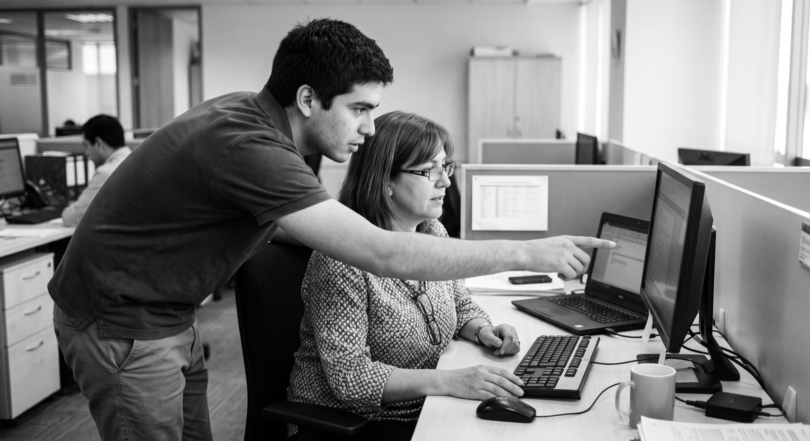Técnico de soporte TI ayudando a una usuaria en la oficina
